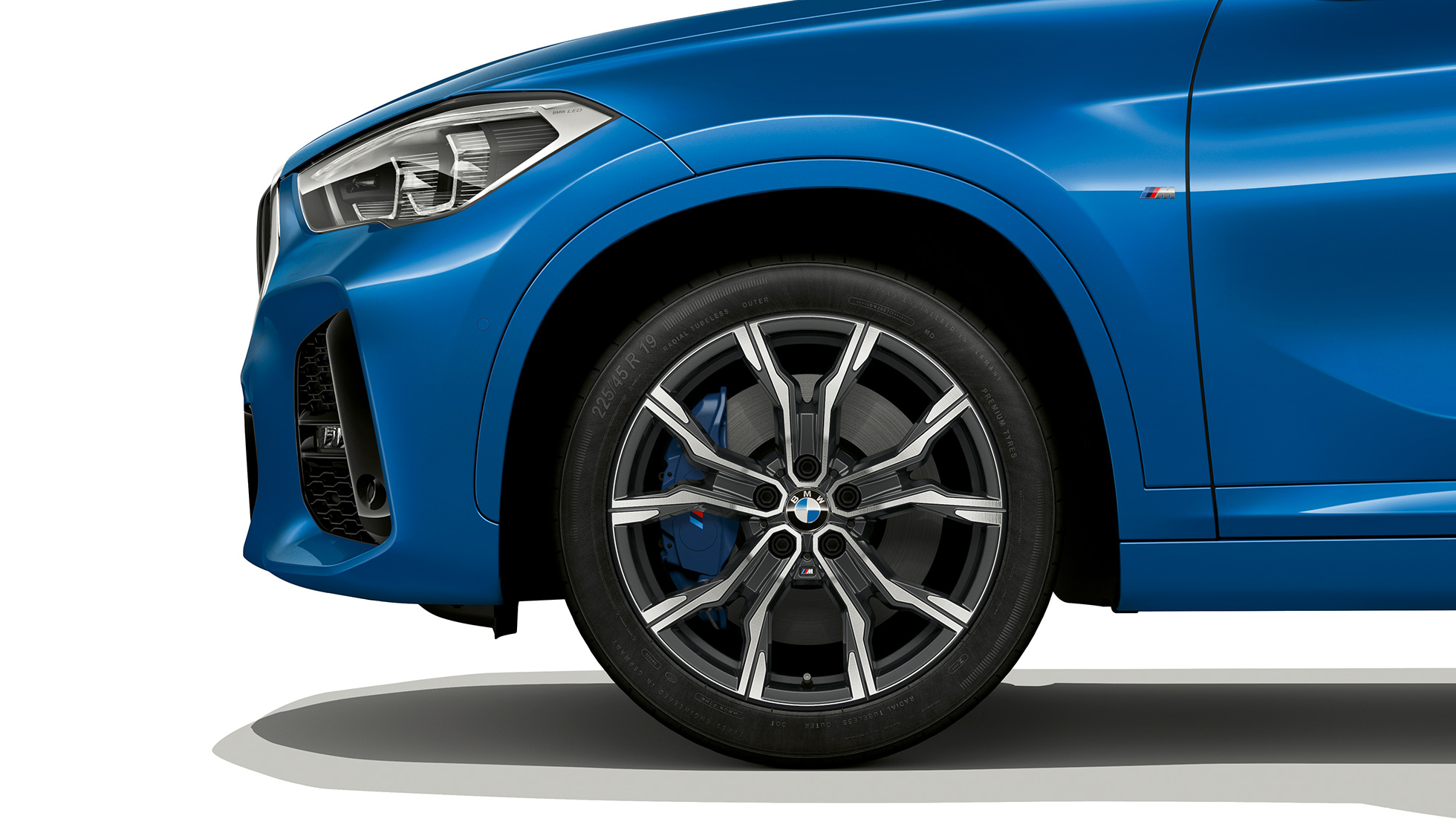 BMW X1, M Sport modelis, vieglmetāla disks. BMW X1, M Sport modelis, skats no sāniem ar vieglmetāla diska tuvplānu.