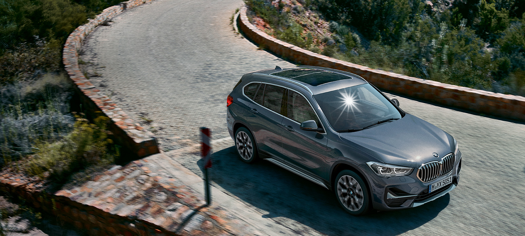 BMW X1, trīs ceturtdaļu skats no priekšpuses. BMW X1, trīs ceturtdaļu skats uz braucošu automobili uz kalnu ainavas fona.