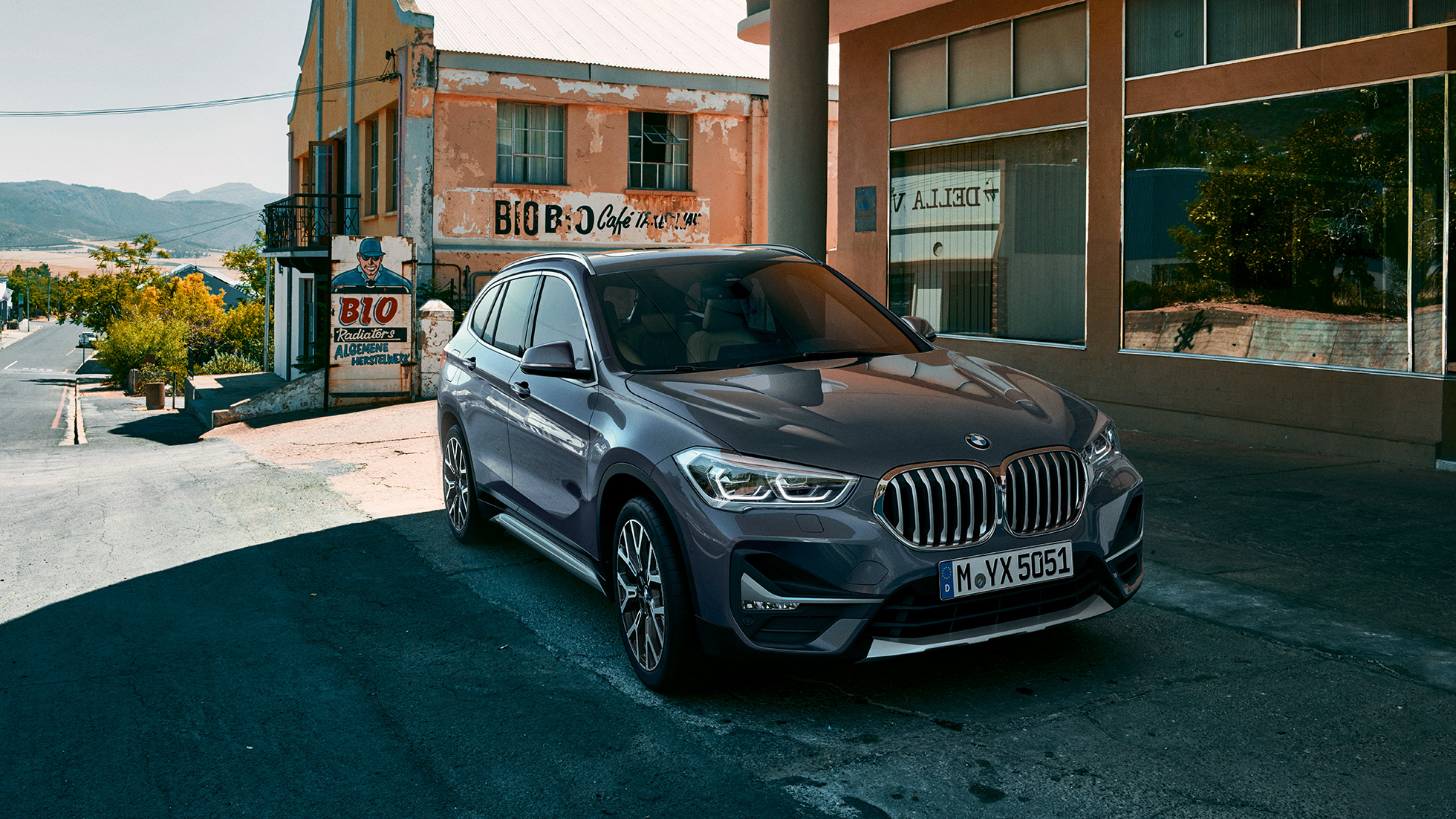BMW X1, trīs ceturtdaļu skats no priekšpuses. BMW X1, trīs ceturtdaļu skats no priekšpuses uz braucošu automobili uz pilsētas ainavas fona.