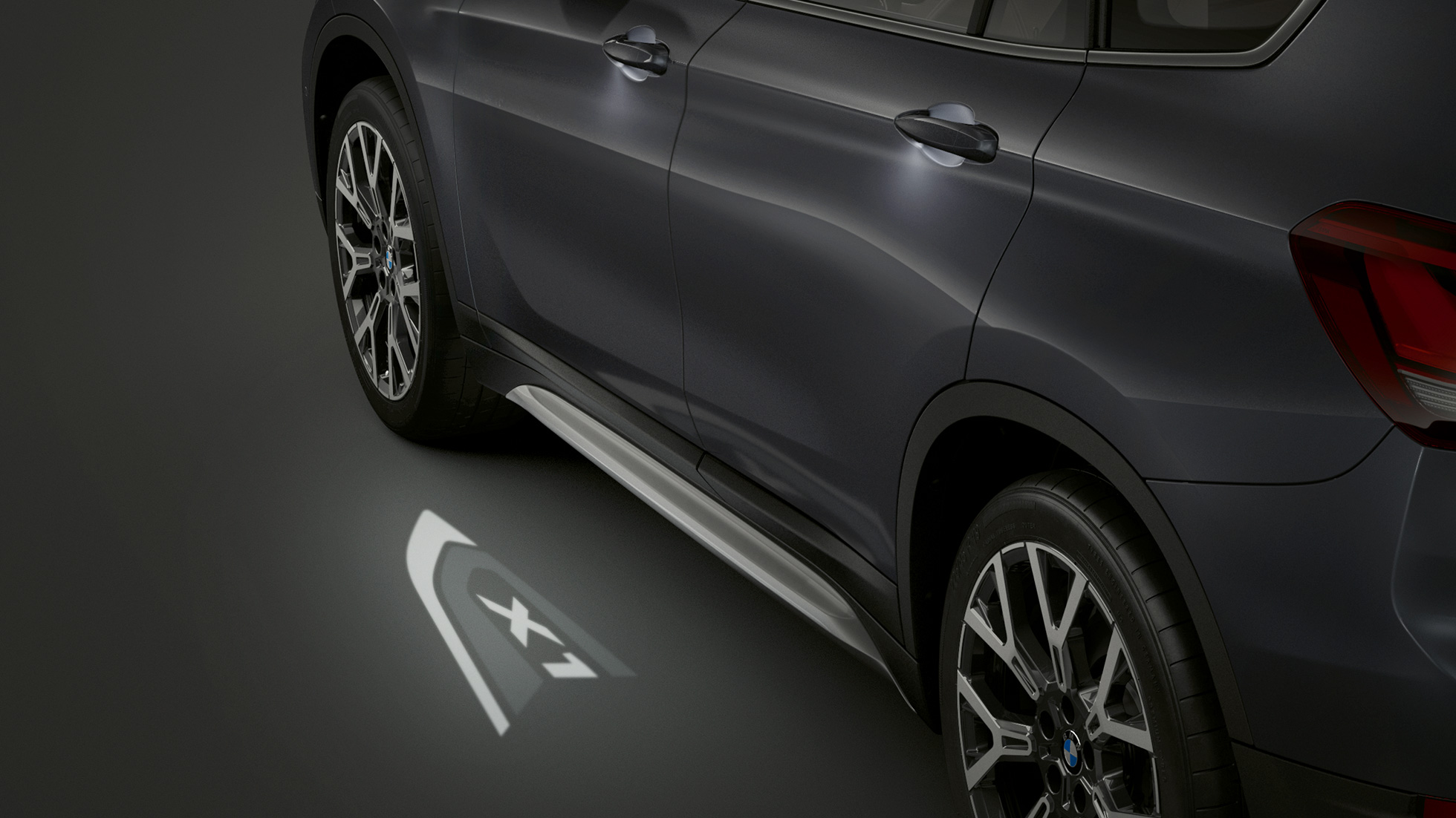 BMW X1, LED projekcija “X1”. BMW X1, skats no sāniem ar fokusu uz LED projekciju “X1”.