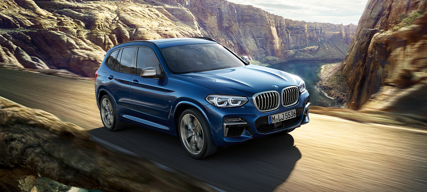 BMW X3 M40i, skats uz braucošu automobili uz kanjona fona BMW X3 M40i, skats uz braucošu automobili uz kanjona fona