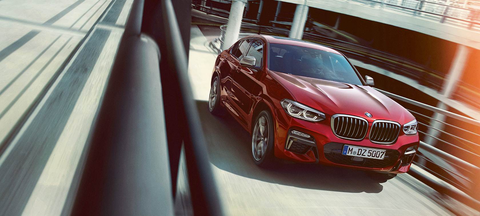 BMW X4, braucot pa daudzstāvu autostāvvietu BMW X4 G02 2018, Flamenco Red krāsa ar mirdzuma efektu, trīs ceturtdaļu skats, braucošs automobilis daudzstāvu autostāvvietā