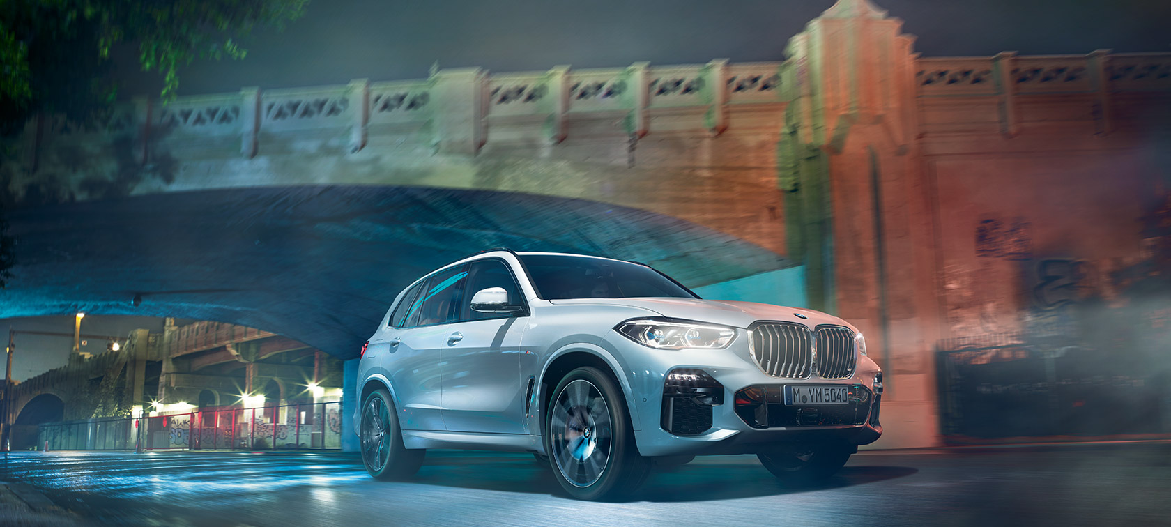 BMW X5 G05 2018, metāliska Mineral White krāsa, trīs ceturtdaļu priekšpuses skats, naktī braucošs automobilis