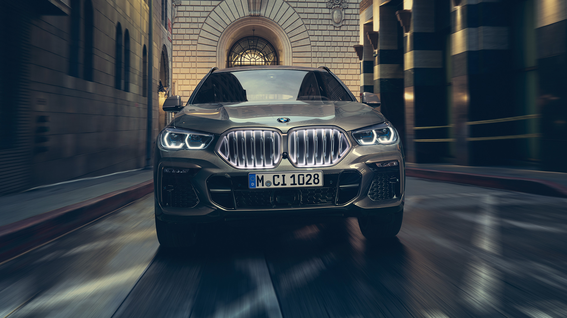 BMW X6 ar BMW “Iconic Glow” elipsveida režģi. BMW X6 priekšpuses skats uz pilsētas fona.