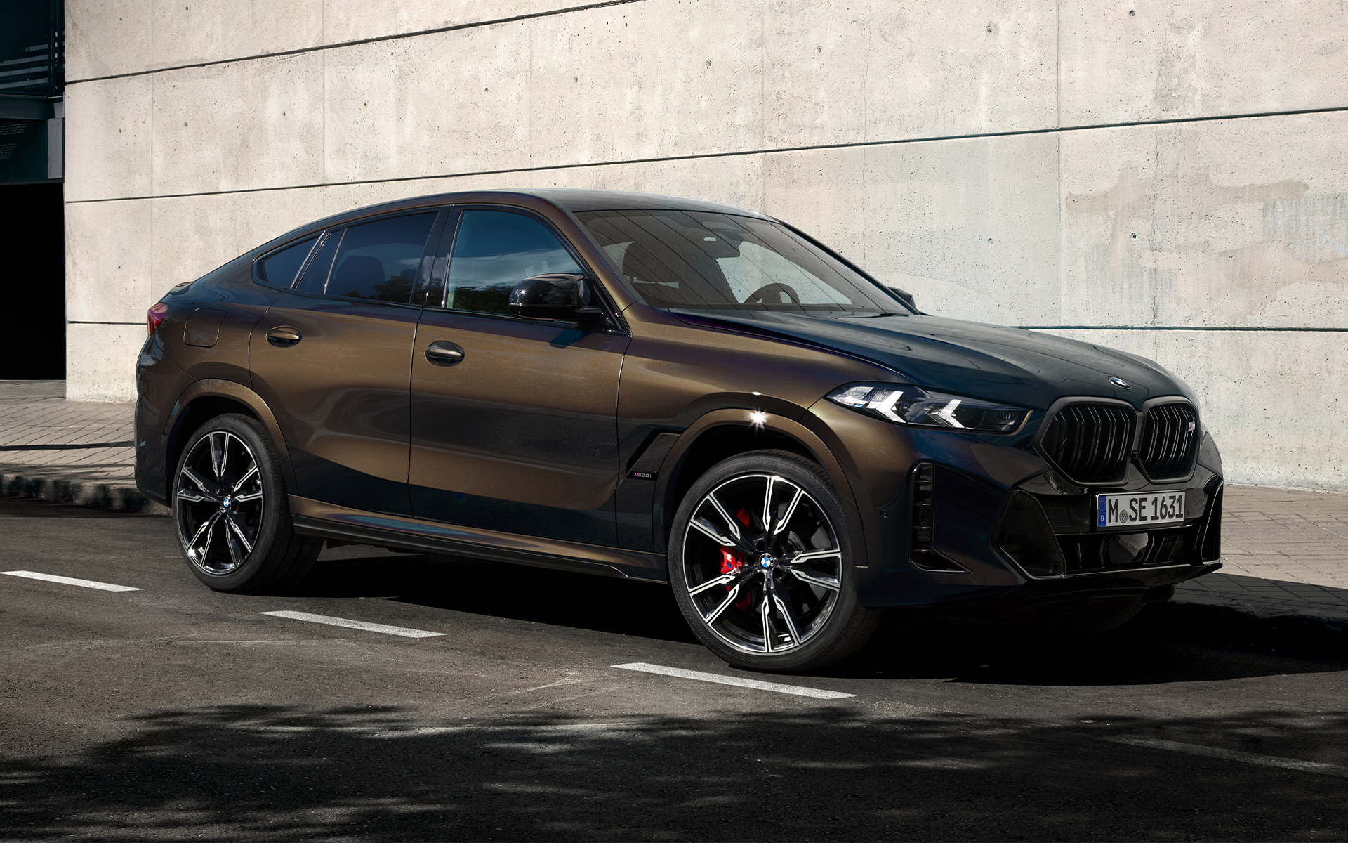 BMW X6 M60i, G06, metāliskā Pyrite Brown krāsā BMW X6 M60i, G06, BMW Individual metāliskā Pyrite Brown krāsā, divu trešdaļu sānskats, stāvvietā novietots automobilis