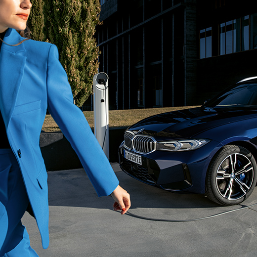 Uzlādes process ar BMW, ejoša sieviete priekšplānā