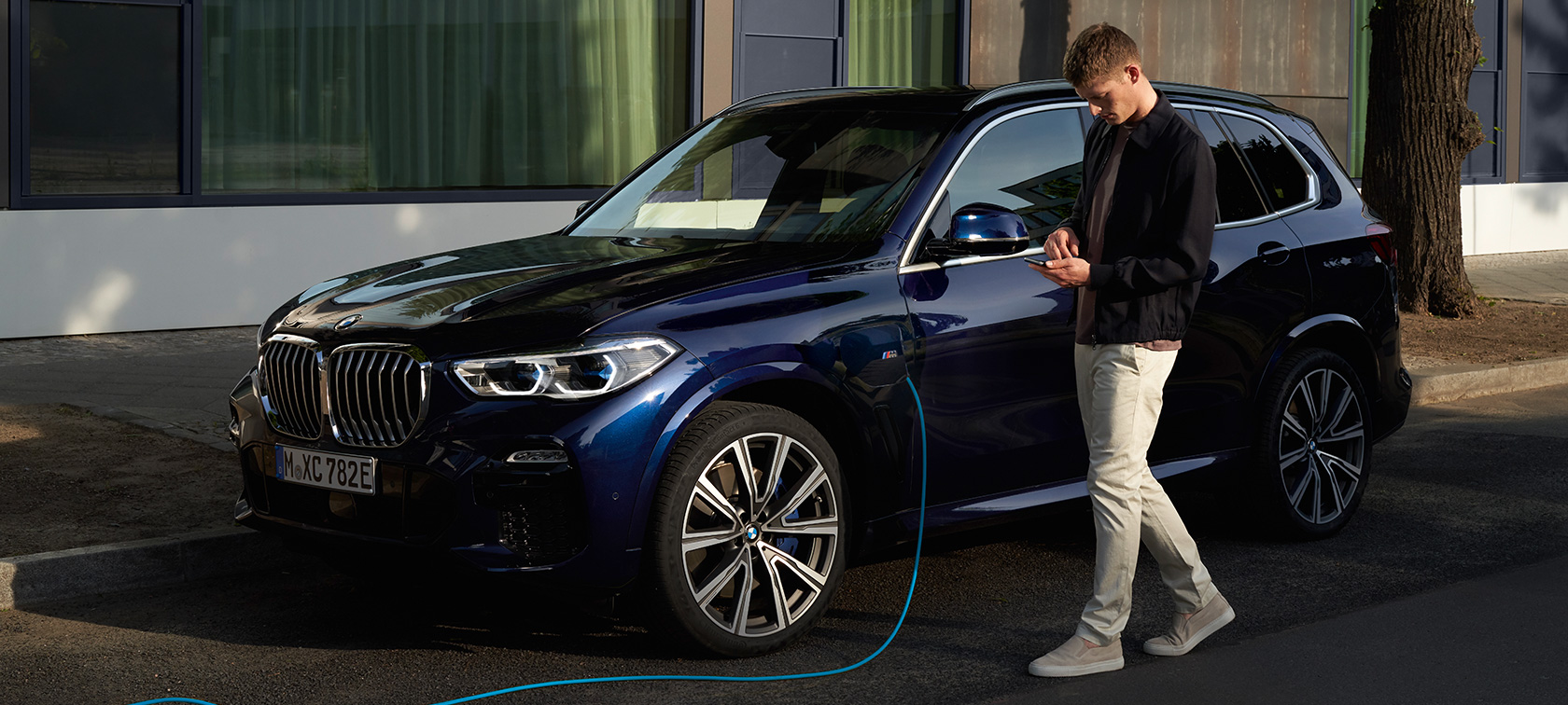 Vīrietis lieto My BMW lietojumprogrammu viedtālrunī Vīrietis viedtālrunī lieto My BMW lietojumprogrammu BMW ConnectedDrive portālā, veicot sava BMW X5 hibrīdauto uzlādi