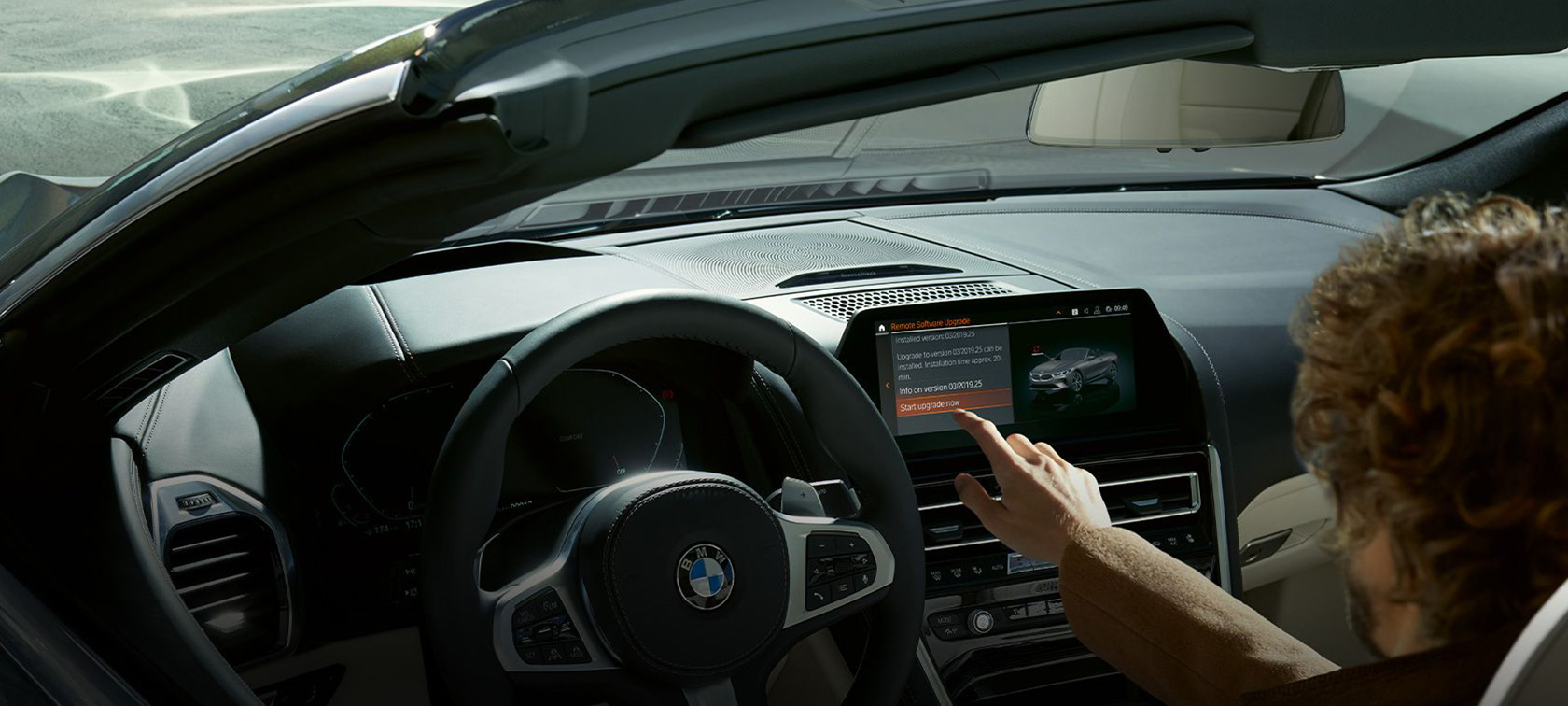 BMW attālā programmatūras jaunināšana Vīrietis sēž BMW un sāk BMW attālo programmatūras jaunināšanu