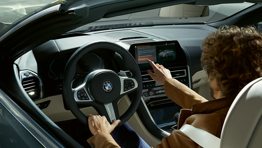Attālinātais programmatūras atjauninājums Attālā programmatūras jaunināšana, vīrietis sēž BMW automobilī un izmanto vadības displeju