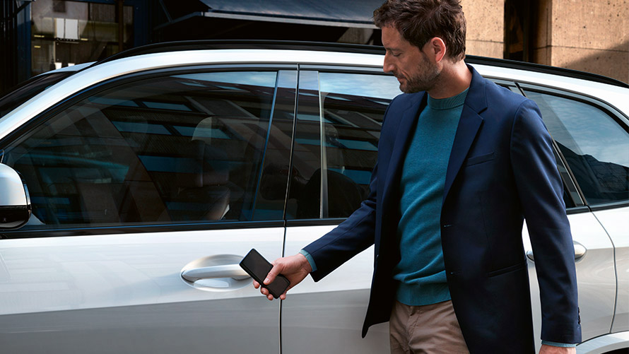Digitālā atslēga Vīrietis atver BMW ar digitālo atslēgu viedtālrunī