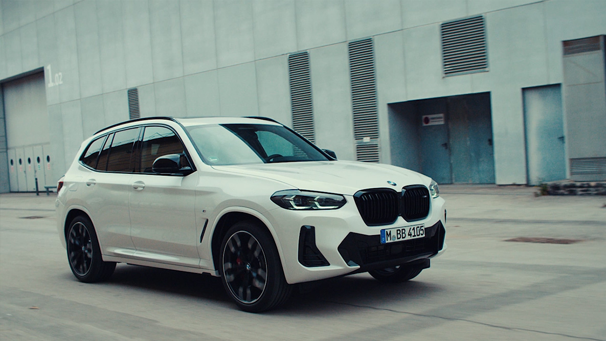 BMW braucienā uz rūpnieciskas ainavas fona, BMW automobiļa atpakaļatdošana BMW automobiļa atpakaļatdošana, BMW baltā krāsā, BMW trīs ceturtdaļu priekšpuses skats, uz rūpnieciskas ainavas fona, braucienā
