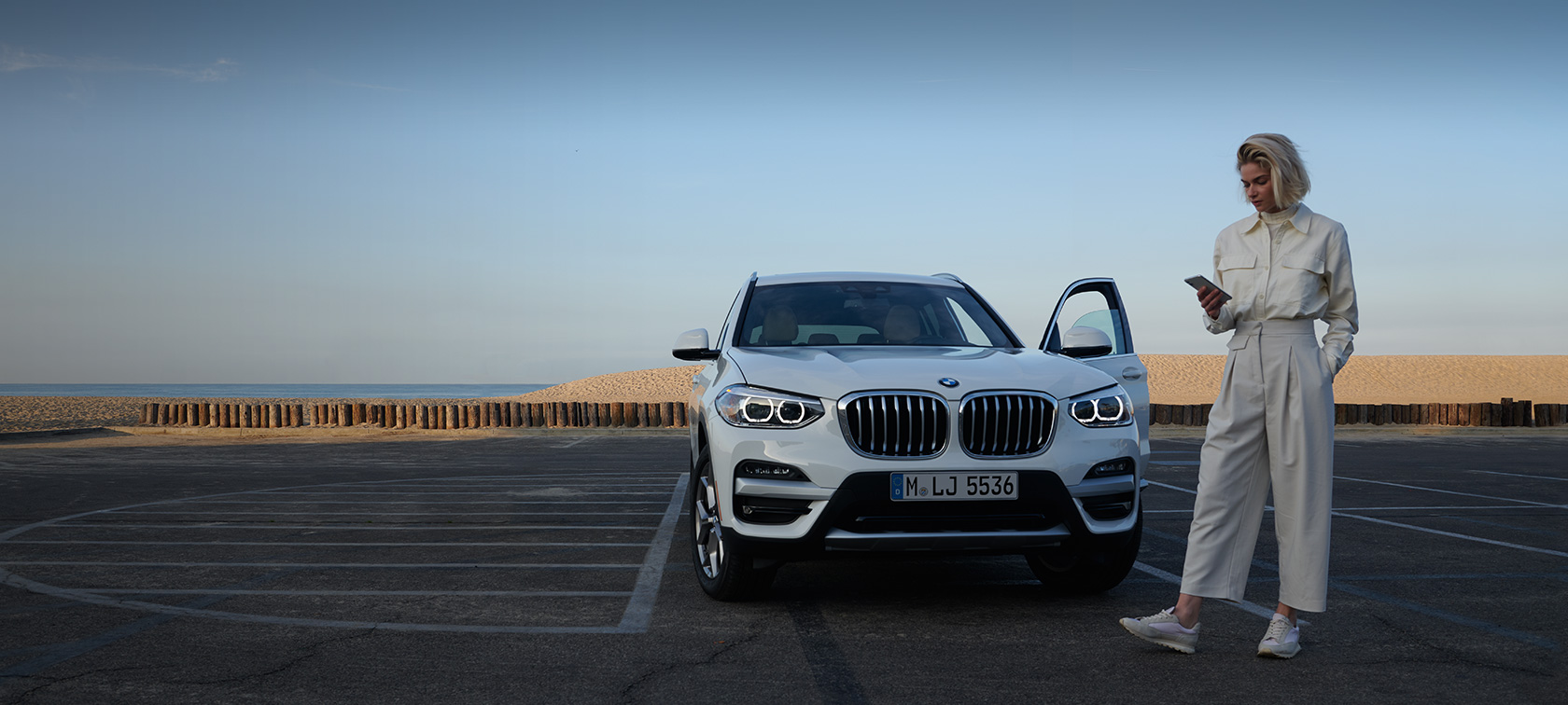 Sieviete darbojas ar My BMW lietojumprogrammu viedtālrunī Sieviete darbojas ar My BMW lietojumprogrammu viedtālrunī