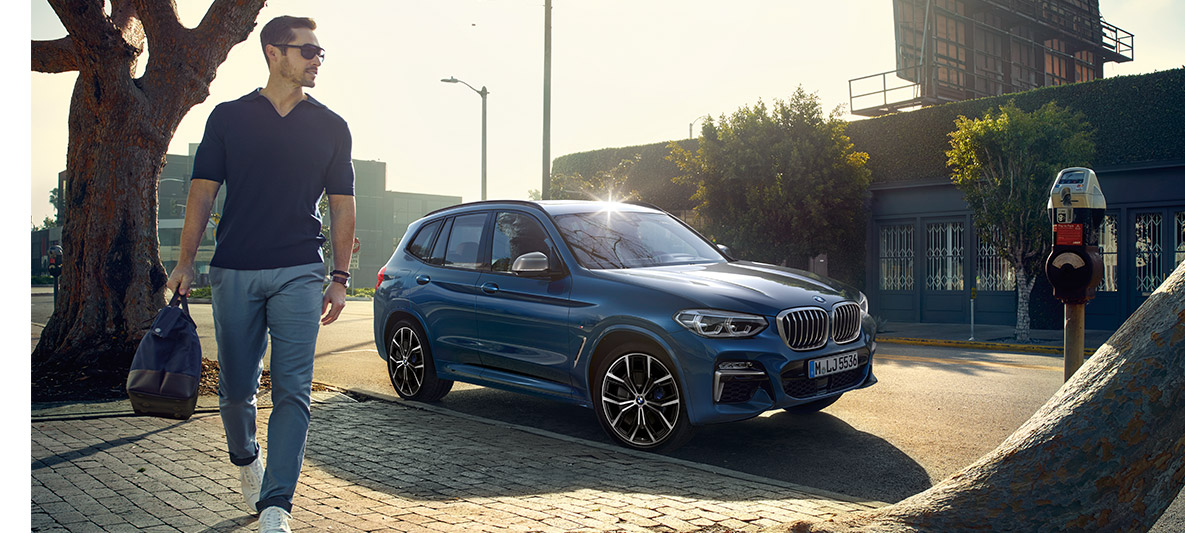 Vīrietis ar saulesbrillēm uz zila BMW fona Vīrietis ar saulesbrillēm uz zila BMW fona