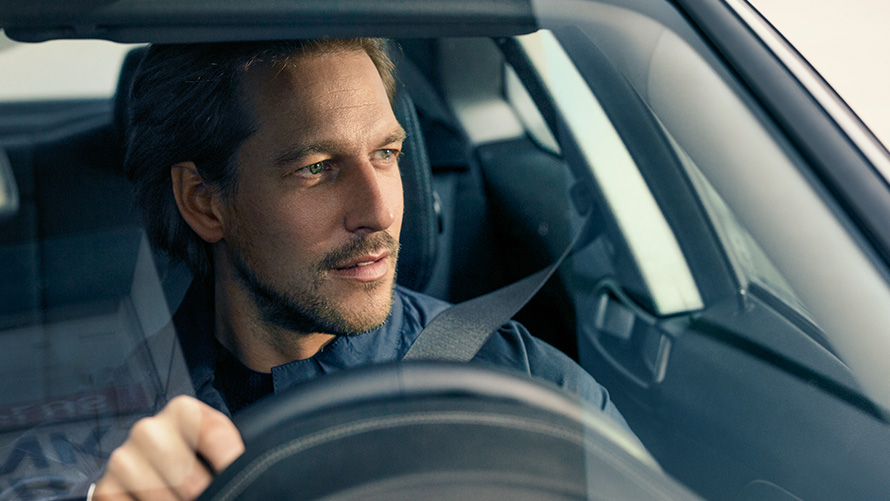 Vīrietis vada BMW Vīrietis vada BMW, skatoties cauri vējstiklam