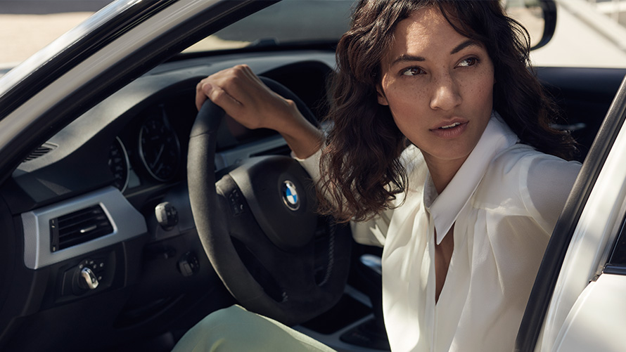 BMW Value Service BMW servisa kliente skatās cauri sava BMW atvērtajām durvīm