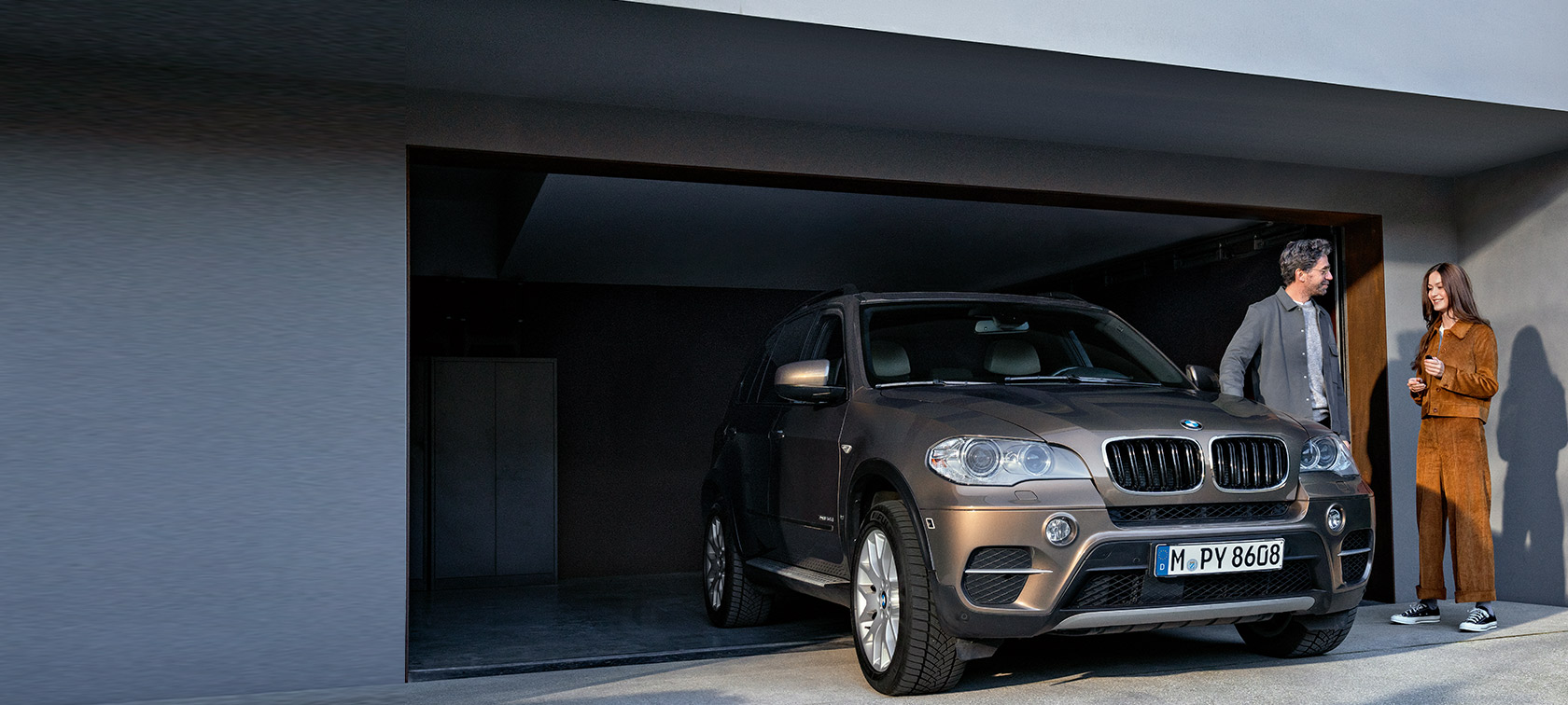 BMW Value Service BMW Value Service, vīrietis un sieviete uz garāžas fona ar BMW X5