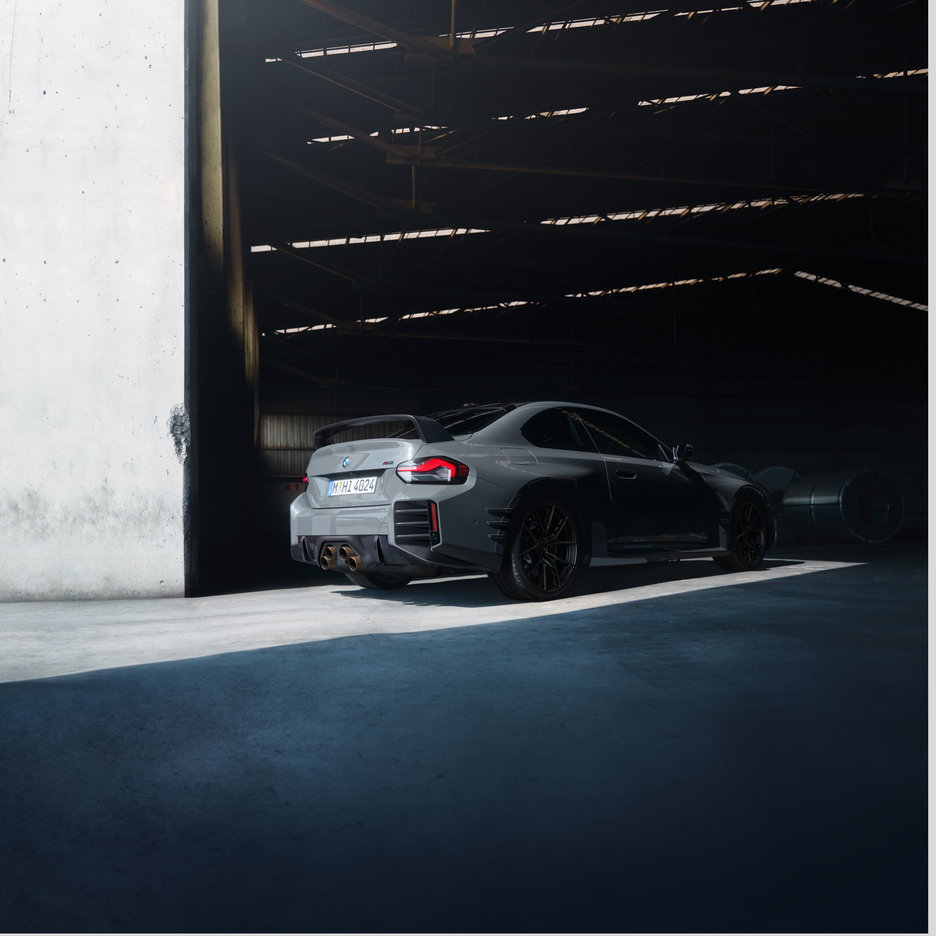 BMW stāv pie lielas halles vārtiem